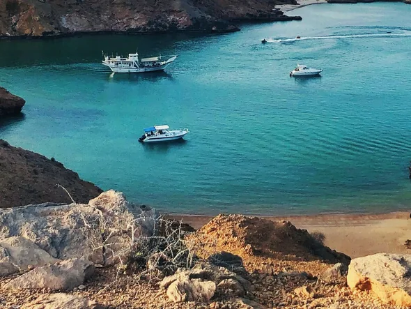 Turquoise bay with a boat on the Omani coast
