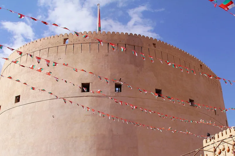 Nizwa Fort's round tower strung with Omani flag bunting