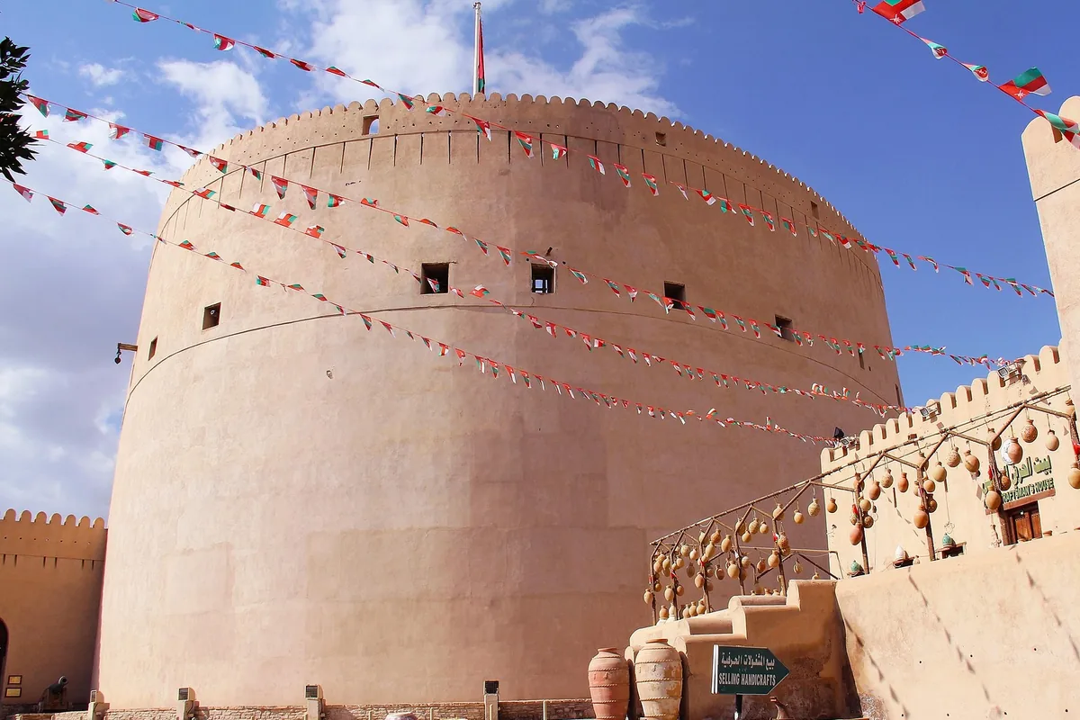 Nizwa Fort's round tower, hung with Omani flags
